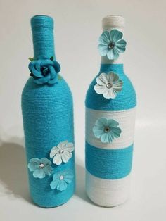 two blue and white vases with flowers on the top one is made out of yarn