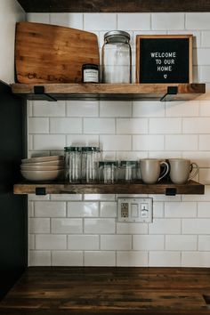 the shelves above the kitchen counter are filled with dishes and cups, along with a sign that says welcome home