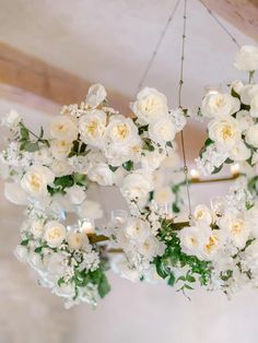 a chandelier filled with white flowers and greenery