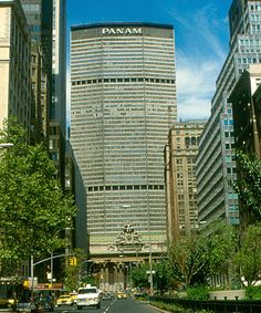 a city street with tall buildings and cars driving down the road in front of it