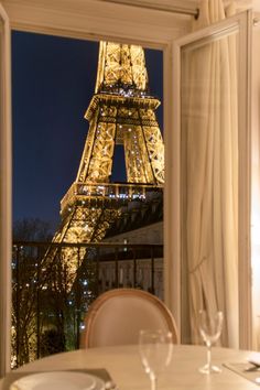 the eiffel tower is lit up at night from an open window in a restaurant