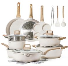 an assortment of white pots and pans with wooden utensils next to them