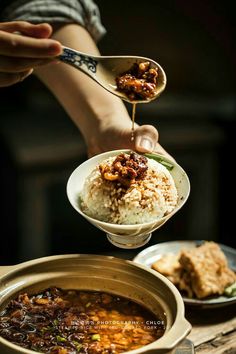 a person is spooning food out of a bowl with rice and meat in it