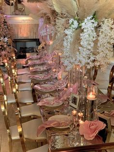 a long table is set with pink and white flowers, candles, and place settings