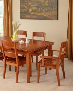 a dining room table with four chairs and a vase on the table in front of it