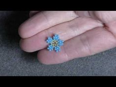 a person holding a small blue flower in their hand and wearing a ring on it