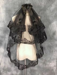 a mannequin wearing a black veil with lace on it's neck and sleeves