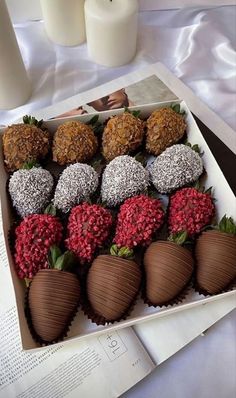 chocolate covered strawberries in a box on top of a table next to a candle