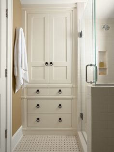 a white bathroom with black handles and drawers