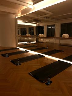 there are many empty yoga mats on the floor in this large room with mirrors above them