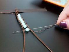 someone is sewing beads on a piece of string