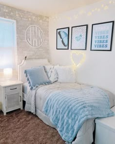 a bedroom with white brick walls and blue comforter on the bed, two framed pictures above it