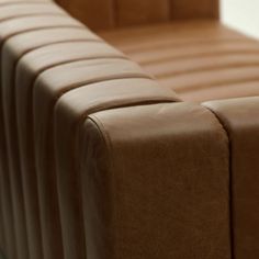 a close up view of the back end of a brown leather couch with pleated cushions