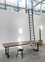 an empty room with a ladder leaning up against the wall next to a long table