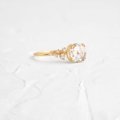 a gold ring with an oval cut diamond and two small round diamonds on the side