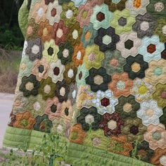 two quilts that are sitting on the ground next to each other, one is green and the other is brown