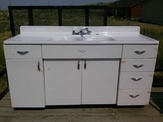 a white sink sitting on top of a wooden floor next to a metal rail fence