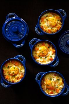 four blue dishes filled with food sitting on top of a table next to each other