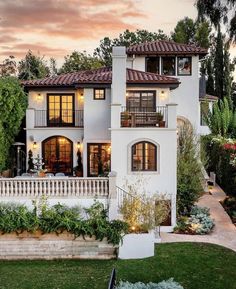 a large white house with many windows and balconies on the front porch, surrounded by greenery