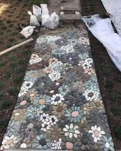 a walkway made out of rocks and stones with flowers painted on the ground next to it