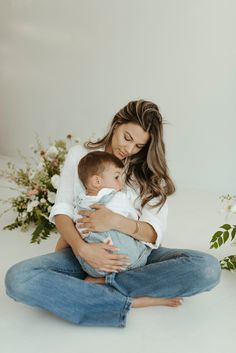 a woman sitting on the floor holding a baby