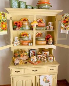 a yellow china cabinet with dishes on it