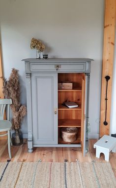 a room with a rug, chair and cabinet in the corner that has been painted blue