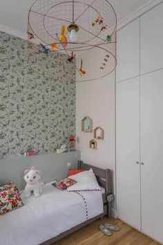 a child's room with a bed, dresser and toy birdcage hanging from the ceiling