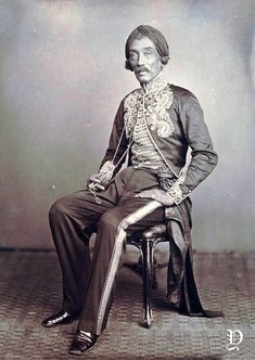 an old photo of a man sitting on a chair