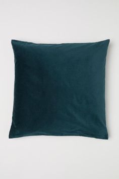 a dark green pillow sitting on top of a white wall