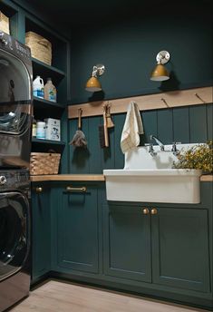 a washer and dryer in a kitchen with green painted cabinets, wood flooring and open shelving