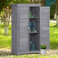 an outdoor storage shed with its doors open and gardening tools in the bottom shelf next to it