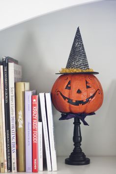 a halloween pumpkin sitting on top of a book shelf