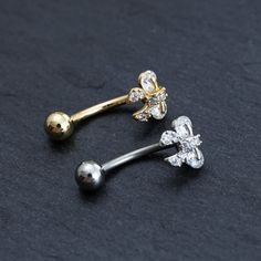 two different types of piercings on a black surface, one is gold and the other is silver