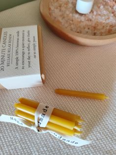 three yellow candles sitting on top of a table next to a box and some paper