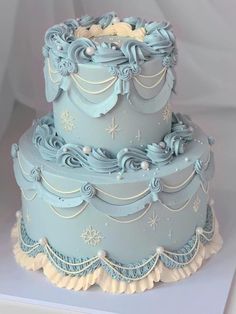 a three tiered blue cake with frosting and snowflakes on the top