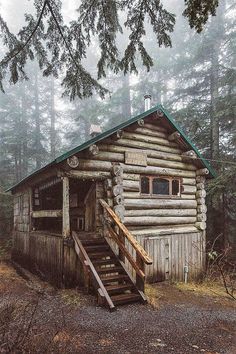 an old log cabin in the woods with stairs leading up to it's roof