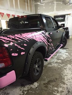 a black truck with pink paint on it's tailgates in a garage