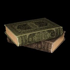 two old books are stacked on top of each other in front of a black background