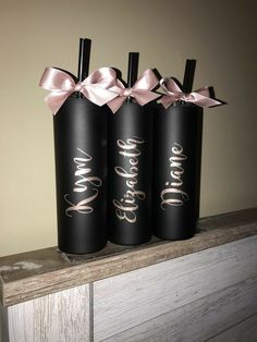 three black wine bottles with pink bows on top