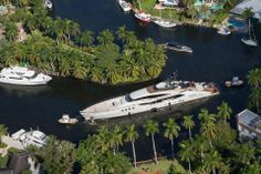 an aerial view of several boats in the water near palm trees and houses on land