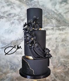 a black and gold wedding cake with flowers on top