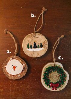 three ornaments are hanging from twine on a wooden table, each decorated with an ornament