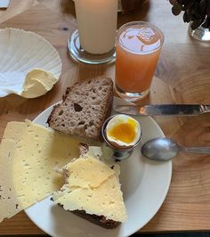 a white plate topped with different types of cheese and bread next to glasses of orange juice