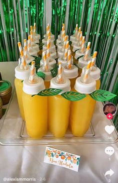 there are many drinks in yellow cups with straws on the top and green sticks sticking out of them