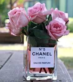 some pink roses in a glass vase with a label that says no 5 chanel