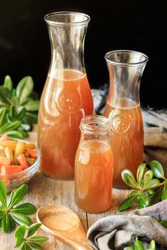 three pitchers filled with liquid sitting on top of a wooden table next to other items