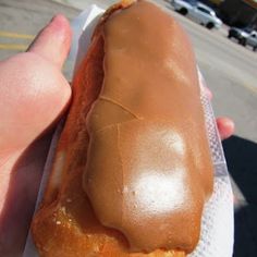 a person is holding a hot dog on a paper towel in front of a parking lot