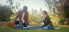 two people sitting on a blanket in the grass