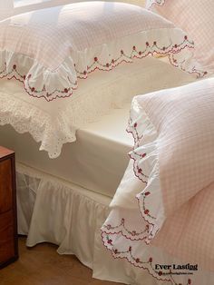 a bed with pink and white bedspreads on it's sides next to a window